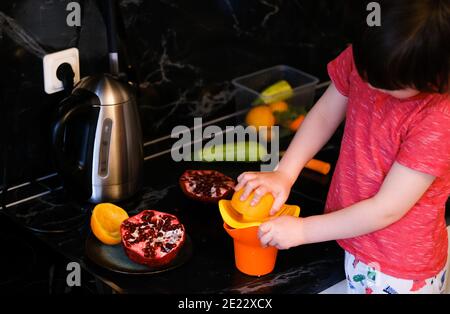 Kleiner Junge, der frischen Orangensaft zubereitet und Orangen in der Küche quetscht. Stockfoto