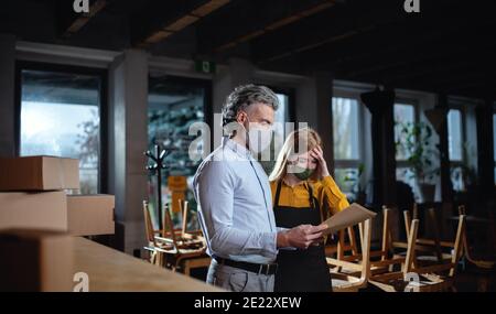 Frustrierter Besitzer mit Kellnerin in geschlossenem Cafe, kleine Unternehmen geschlossen wegen Coronavirus. Stockfoto