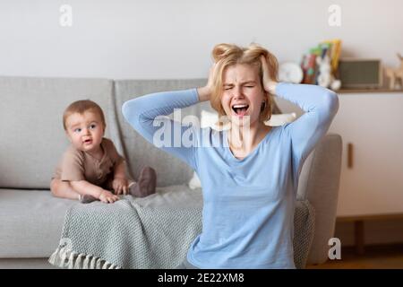 Gestresste Mutter mit Kopfschmerzen mit Baby zu Hause Stockfoto