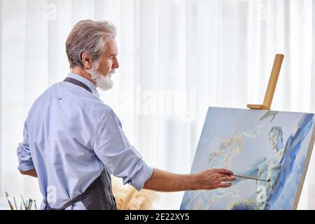 Maler erstellen Meisterwerk, ältere männliche Arbeiten auf Leinwand, mit Farben, Pinsel, Staffelei und andere Werkzeuge Stockfoto