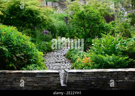 juni blakes Garten, Pfad, Steinmauer, Steinweg, gepflasterten Weg, Gartengestaltung, gemischte Betten, gemischte Grenzen, gemischte Bepflanzung Farbschema, RM-Blumenmuster Stockfoto