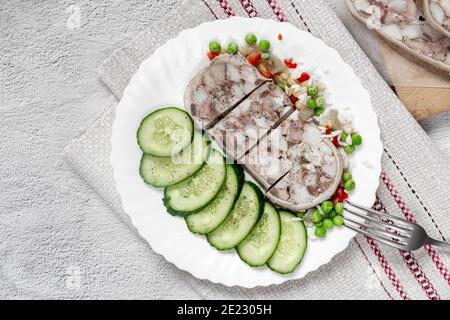Auf dem Tisch auf einem Teller mit köstlichen Fleisch Vorspeise: Gefüllt mit Fleisch und Speck Schweinefleisch Magen, in Scheiben geschnitten, neben Gemüse und frischen Gurken. Top Vie Stockfoto