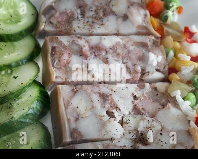 Auf dem Tisch auf einem Teller mit köstlichen Fleisch Vorspeise: Gefüllt mit Fleisch und Speck Schweinefleisch Magen, in Scheiben geschnitten, neben Gemüse und frischen Gurken. Top Vie Stockfoto
