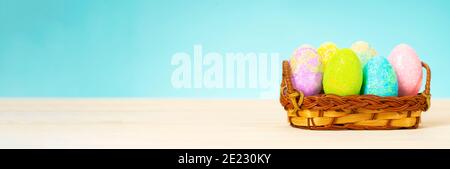 Bunte ostereier im Korb auf dem Tisch auf blauem Hintergrund. Stockfoto