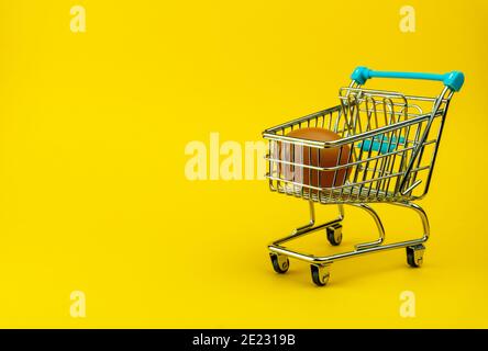 Braunes Hühnerei in kleinem Einkaufswagen, Mini-Cart mit einem Ei im Inneren Stockfoto