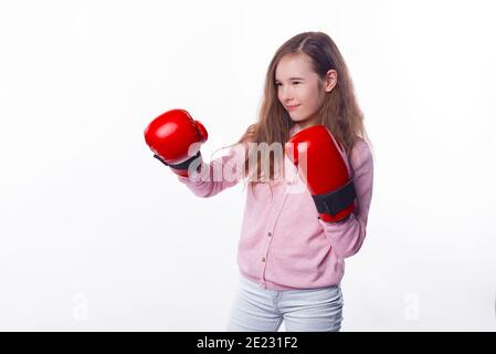 Konzentriertes kleines Mädchen trägt einige rote Handschuhe für Box über weißem Hintergrund. Stockfoto