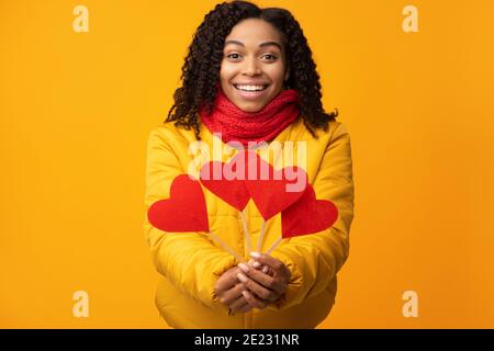 Glückliche Afrikanische Frau Zeigt Papierherzen Zur Kamera, Gelber Hintergrund Stockfoto