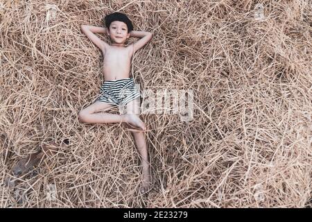 Porträt eines niedlichen kleinen asiatischen Jungen lächelnd und liegend auf Heu, Reisstroh. Stockfoto