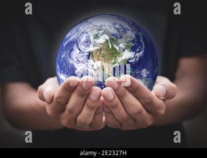 Tag der Erde. Menschliche Hände halten global über verschwommenem schwarzen Hintergrund. Erde in Händen. Speichern Sie die Erde. Umwelt-Konzept. Stockfoto