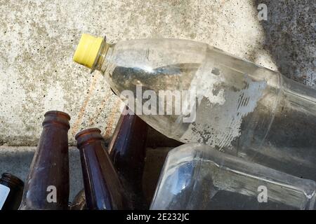 Nahaufnahme von Kunststoff- und Glasflaschen, Müll, der auf dem Boden eines Hauses liegt und entsorgt werden muss. Konzept der Umweltverschmutzung. Stockfoto