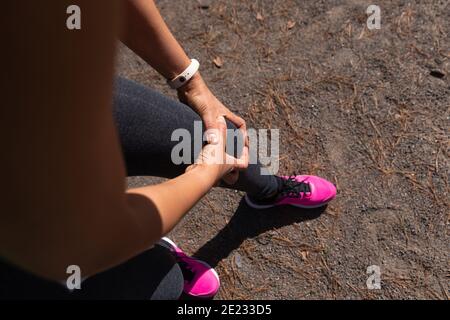 Weibliche Athletin hält die Hände auf dem Knie und fühlt Schmerzen Stockfoto