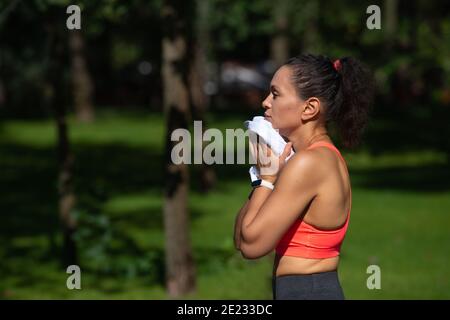 Seitenportrait einer müden jungen Frau, die nach dem Lauftraining ihren Schweiß abwischt. Ausdauertraining im Freien Stockfoto
