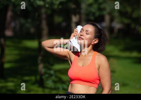 Glücklich sportliche Frau wischen ihr Gesicht mit Handtuch nach produktiven Ausübung im Freien. Stockfoto