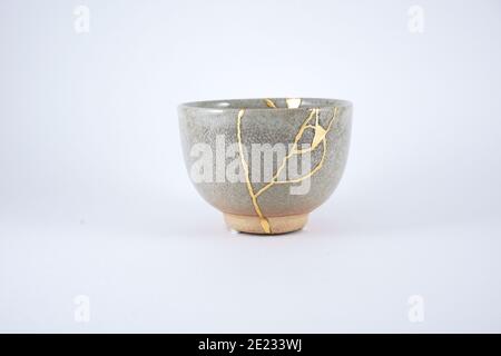 Japanische Kintsugi beige Teetasse, Goldrisse auf antike Keramik. Stockfoto