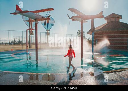 Nette liebenswert kaukasischen lustige Mädchen spielen auf Splash Pad Spielplatz am Sommertag. Saisonal Wassersport Freizeitaktivitäten für Kinder im Freien. Stockfoto