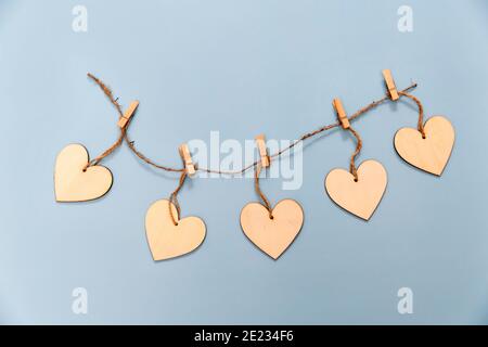 Holzherzen mit Wäscheklammern auf hellblauem Hintergrund an einem Seil befestigt. Speicherplatz kopieren Stockfoto