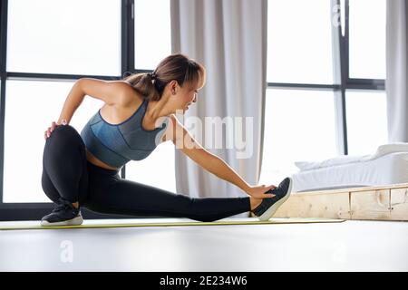 Fit Frau Stretching Beine Muskeln, tun Sport Flexibilität Übungen zu Hause, tragen Sportkleidung. Weibliche führt einen gesunden Lebensstil Stockfoto