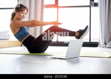 asiatische Frau tut Beckenlift Bauchübungen auf dem Boden, in hellen Raum Studio. Sport, Training, Fitness-Konzept Stockfoto