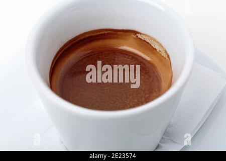 Traditioneller italienischer Espresso in einer kleinen Tasse. Befindet sich auf einer weißen Oberfläche. Nahaufnahme. Stockfoto