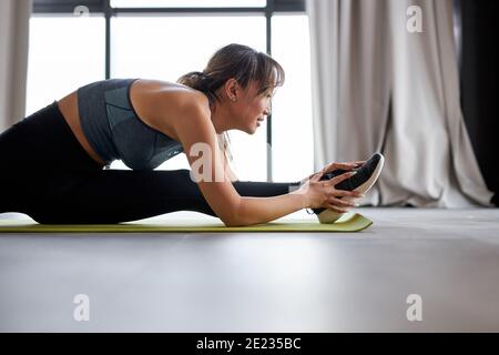 asiatische Frau ist Stretching auf Matte zu Hause, Training, Stretch-Beine. Training, Erholung, gesunde Lebensweise Konzept Stockfoto
