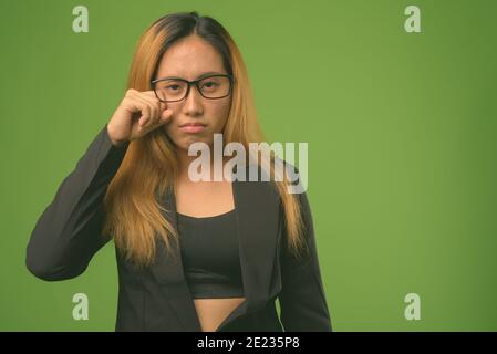 Junge asiatische Geschäftsfrau vor grünem Hintergrund Stockfoto