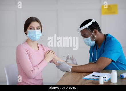 Antiviraler Schutz und Immunisierung. Arzt, der weibliche Patienten gegen Coronavirus impft, Covid-19-Impfstoff injiziert Stockfoto