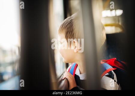 Trauriger kleiner Junge schaut durch das Busfenster. Stockfoto