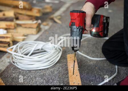 Männliche Hände verwenden Schraubendreher bei Bauarbeiten mit Holz in Innenräumen. Lifestyle-Foto Stockfoto