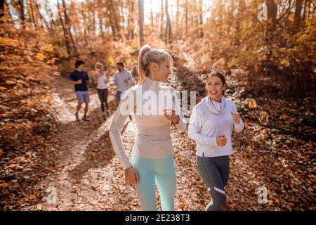 Organisierte kleine Gruppe von Menschen, die im Herbst in den Wäldern laufen. Stockfoto