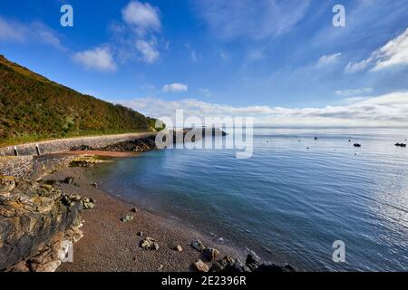 Bild von Bouley Bay an einem sonnigen Morgen mit blauem Himmel mit etwas Wolke, Kiesstrand, glattes Meer und Hafen im Hintergrund. Jersey Channel Islands Stockfoto