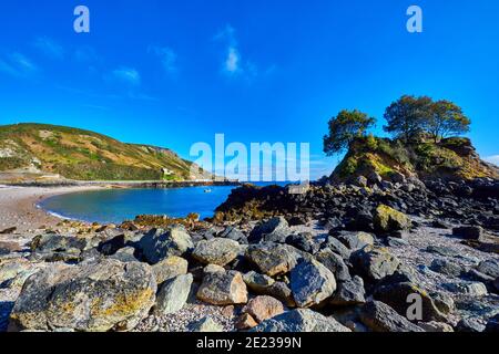 Bild von Bouley Bay an einem sonnigen Morgen mit blauem Himmel, Kiesstrand und einer kleinen Insel mit Bäumen. Jersey Channel Islands Stockfoto