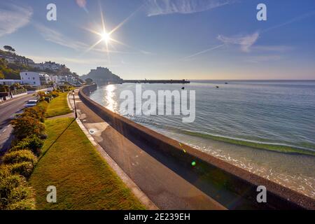 Bild von Gorey Promenade mit Gorey Castle und Hafen im Hintergrund bei Flut mit einem blauen Himmel und frühen Morgensonne. Jersey, Channel Isla Stockfoto