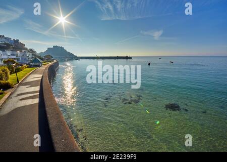 Bild von Gorey Promenade mit Gorey Castle und Hafen im Hintergrund bei Flut mit einem blauen Himmel und frühen Morgensonne. Jersey, Channel Isla Stockfoto