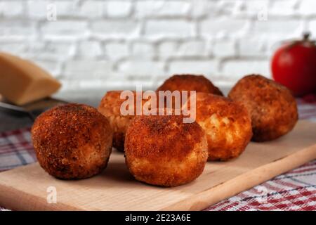 Köstliche heiße italienische arancini - Reisbällchen gefüllt mit Käse Auf einem Brett auf einem alten Holztisch Stockfoto