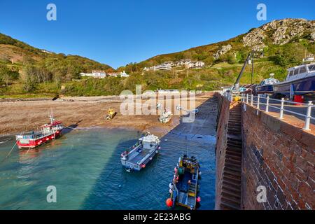 Bild der Bucht Bonne Nuit und des Hafens bei Ebbe mit Felsen, Kieselsteinen und Liegeplätze Chanis, blauer Himmel und Sonnenschein, frühen Morgen, Jersey CI Stockfoto