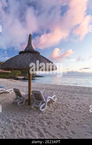 Sonnenaufgang am Strand. Getrocknetes Gras Regenschirme Schatten. Ruhe, Zen, Urlaub, Sommer-Vibes, Entspannung Stimmung auf Stockfoto