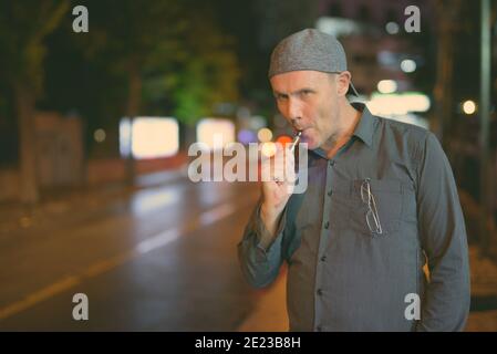 Reifer Mann rauchen Elektronische Zigarette in den Straßen bei Nacht Stockfoto
