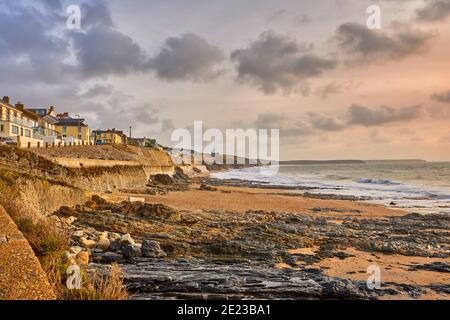 Bild des Strandes von Porthleven, Cornwall mit Felsen, Hütten, Wellen und bewölktem Himmel Stockfoto