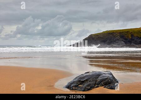 Bild von Poldhu Beach in Cornwall mit Felsen, Wellen, Sand und bewölktem Himmel. Stockfoto