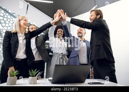 Glückliche multirassische Unternehmer in formeller Kleidung in Business-Büro, geben High Fives zueinander, als ob Erfolg feiern, Einheit oder neu beginnen Stockfoto