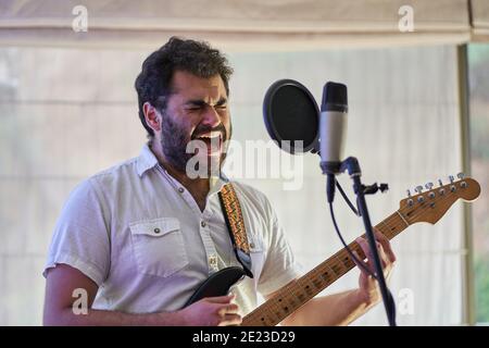 Leidenschaftlicher männlicher Musiker mit E-Gitarre singen begeistert und aufnehmen In einem Studio Stockfoto