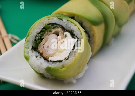 Nahaufnahme einer appetitlich geschnittenen Sushi-Rolle in Avocado verpackt Mit Nori und Käse Stockfoto