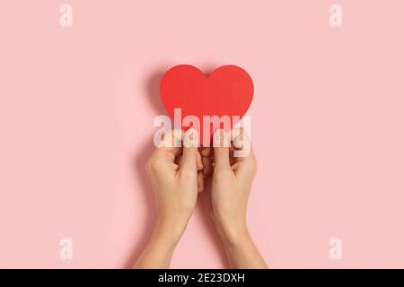 Frau Hände halten leere Valentine-Karte auf rosa Tisch Stockfoto