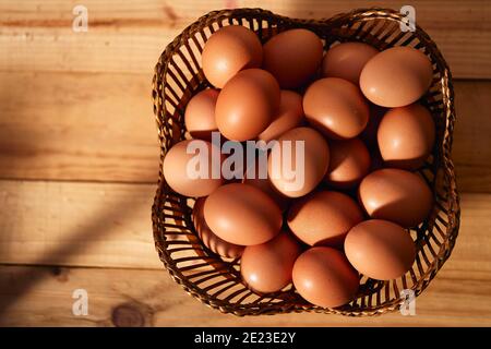Weidenkorb mit frisch gepflückten Feldeiern zum Frühstück Ein Holztisch Stockfoto