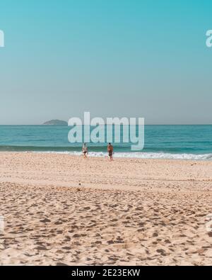 Wunderschöne Aussicht auf ein Paar, das auf dem spazieren geht Sandstrand unter dem blauen Himmel Stockfoto