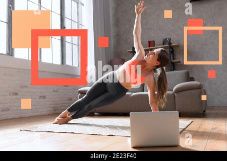 Junge Frau folgt mit einem Laptop ein Fitness-Studio Übungen. Sie ist zu Hause wegen Coronavirus codiv-19 Quarantäne Stockfoto