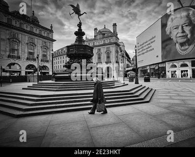 Die Queens Coronavirus-Rede leuchtet auf der Plakatwand des Piccadilly Circus auf, während die UK-Sperre fortgesetzt wird.EIN Mann geht am leeren Piccadilly Circus vorbei. Stockfoto