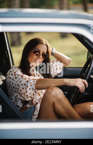 Lächelnde Frau sitzt im Oldtimer. Stockfoto