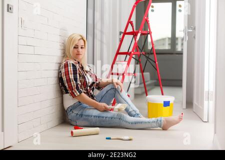 Frau machen Reparatur Stick Tapete haben ein Kopfschmerz Porträt auf Der weiße Wandhintergrund Stockfoto
