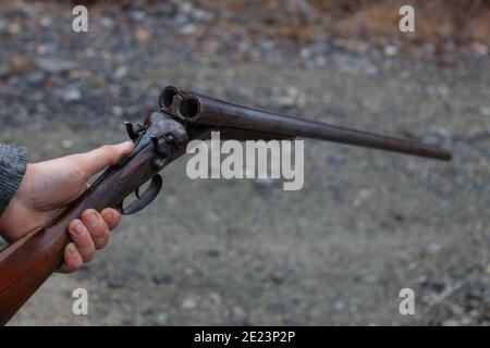 Ein Mann hält eine alte, antike, Doppel-Lauf-Break-Action-Schrotflinte, bereit, zwei Runden in die Bohrung zu laden. Outdoor-Bereich in Squamish, British-Columb Stockfoto